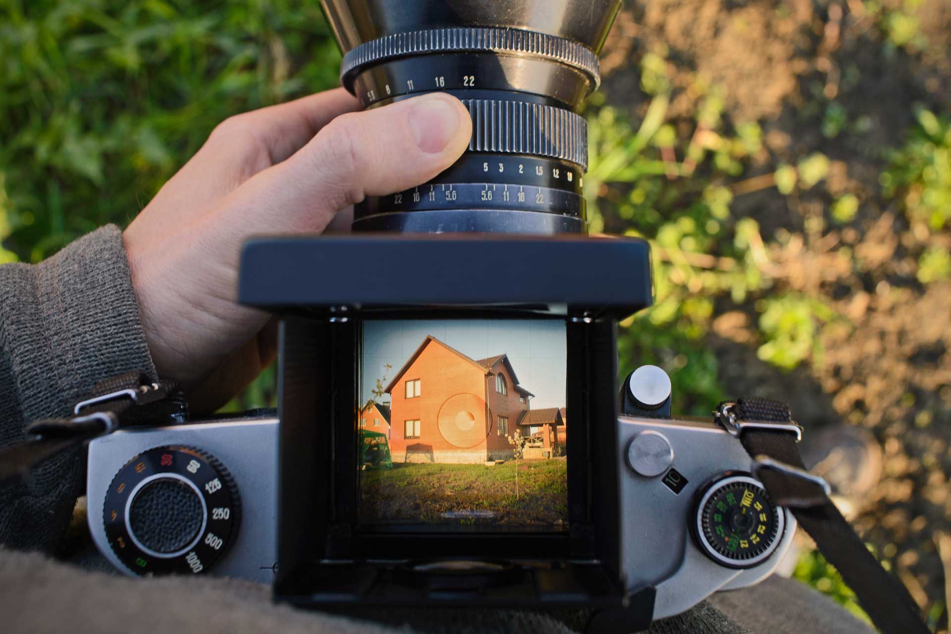 real estate photographer's hand holding a photographic camera with a house on the display